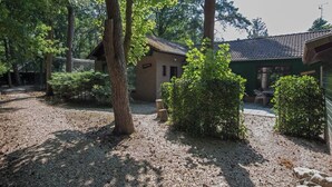 A rustic building with a tiled roof, surrounded by trees and gravel paths.