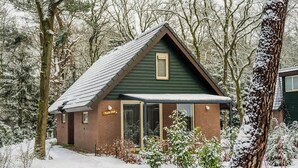 Ein kleines, eingeschossiges Gebäude mit geneigtem Dach, umgeben von schneebedeckten Bäumen.