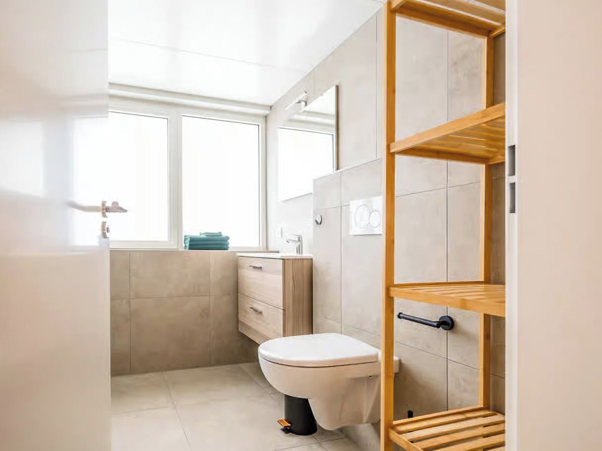 Un baño moderno con inodoro, tocador y estanterías.