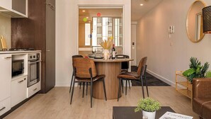 Una cocina moderna con electrodomésticos integrados, un comedor con una mesa redonda y sillas, y una sala de estar con un sofá y una mesita de centro.
