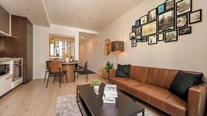 Una sala de estar moderna con un sofá de cuero, un comedor con sillas, una cocina con electrodomésticos y una pared decorada con fotografías enmarcadas.