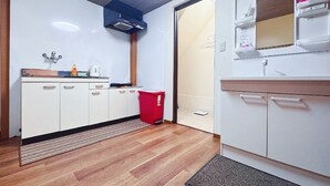 Pieni, käytännöllinen keittiö, jossa on valkoiset kaapit, punainen roskakori, sisäänrakennettu mikroaaltouuni ja pieni ikkuna.
