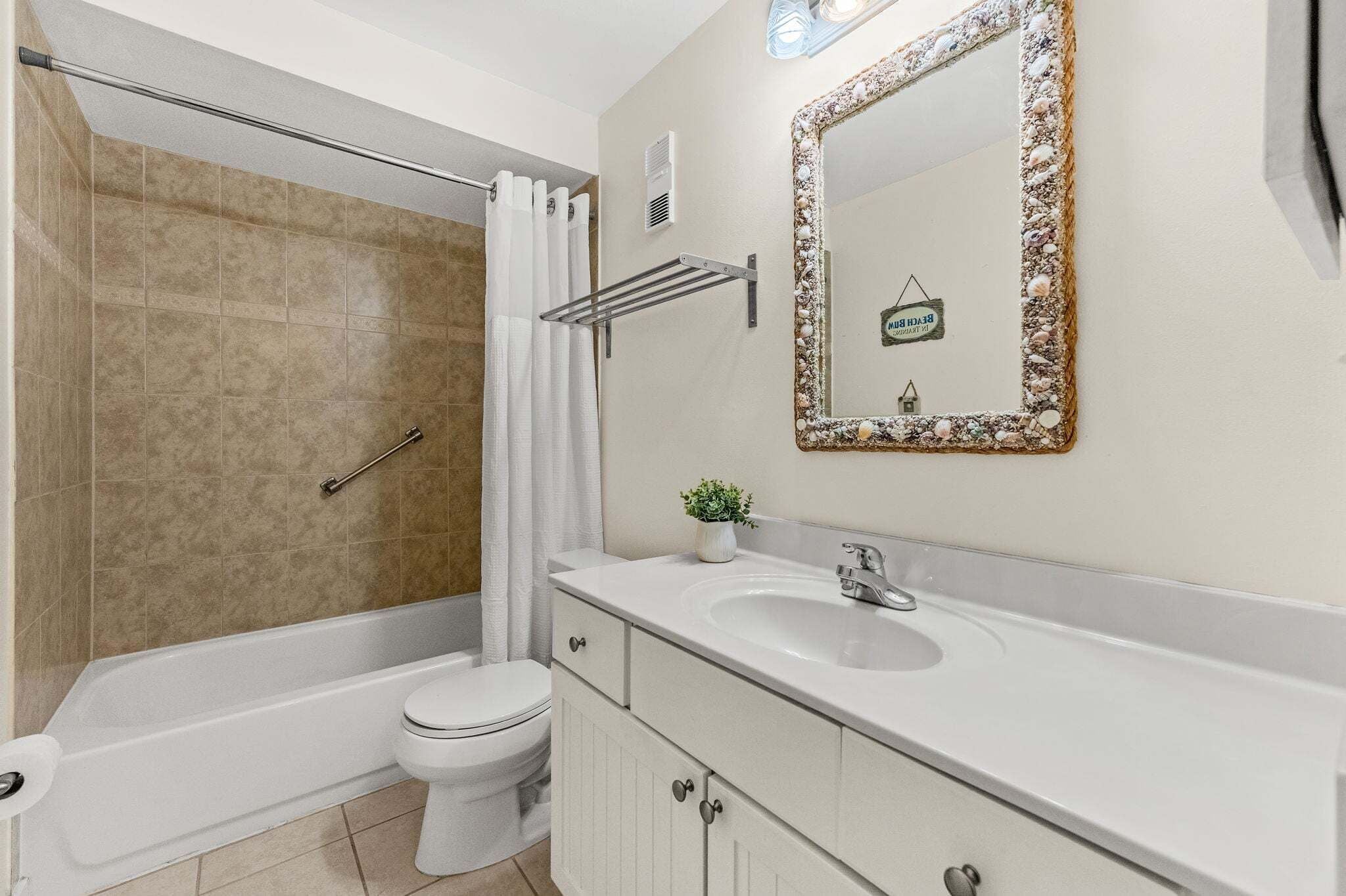Een badkamer met een bad, toilet, wastafel en een spiegel met decoratieve lijst.