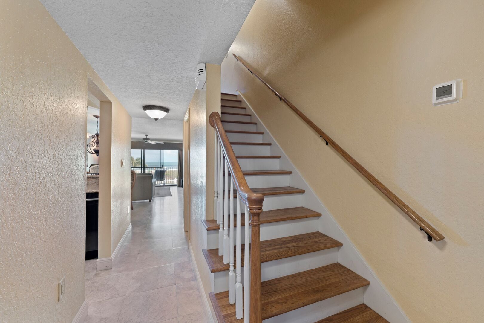 A staircase with wooden steps and white railings, leading to an upper floor.