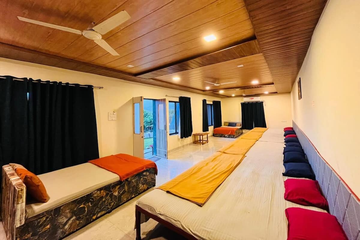 Una habitación con varias camas dispuestas en fila, un ventilador de techo y una puerta que da al exterior.
