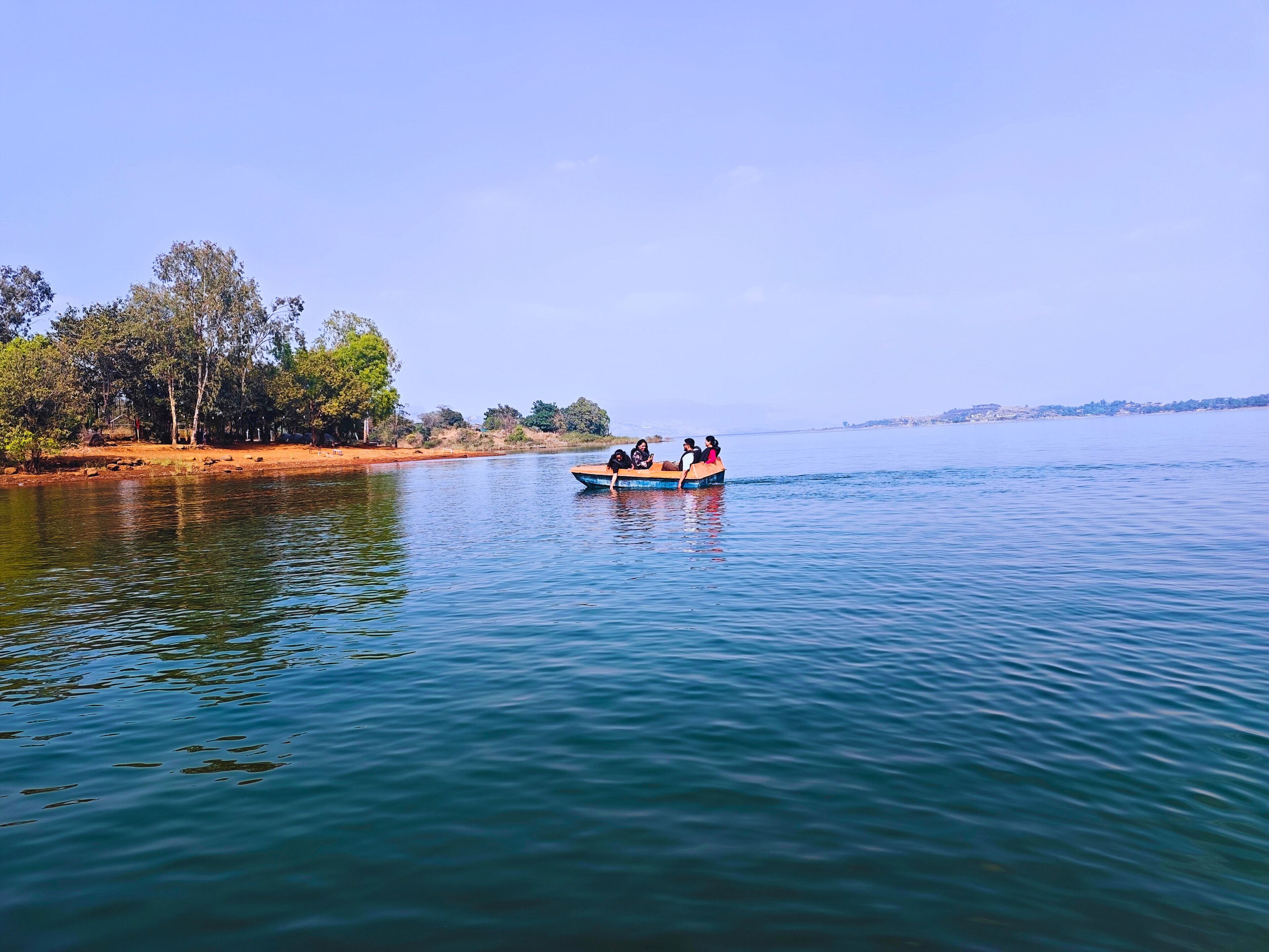 A calm lake with a boat carrying people.