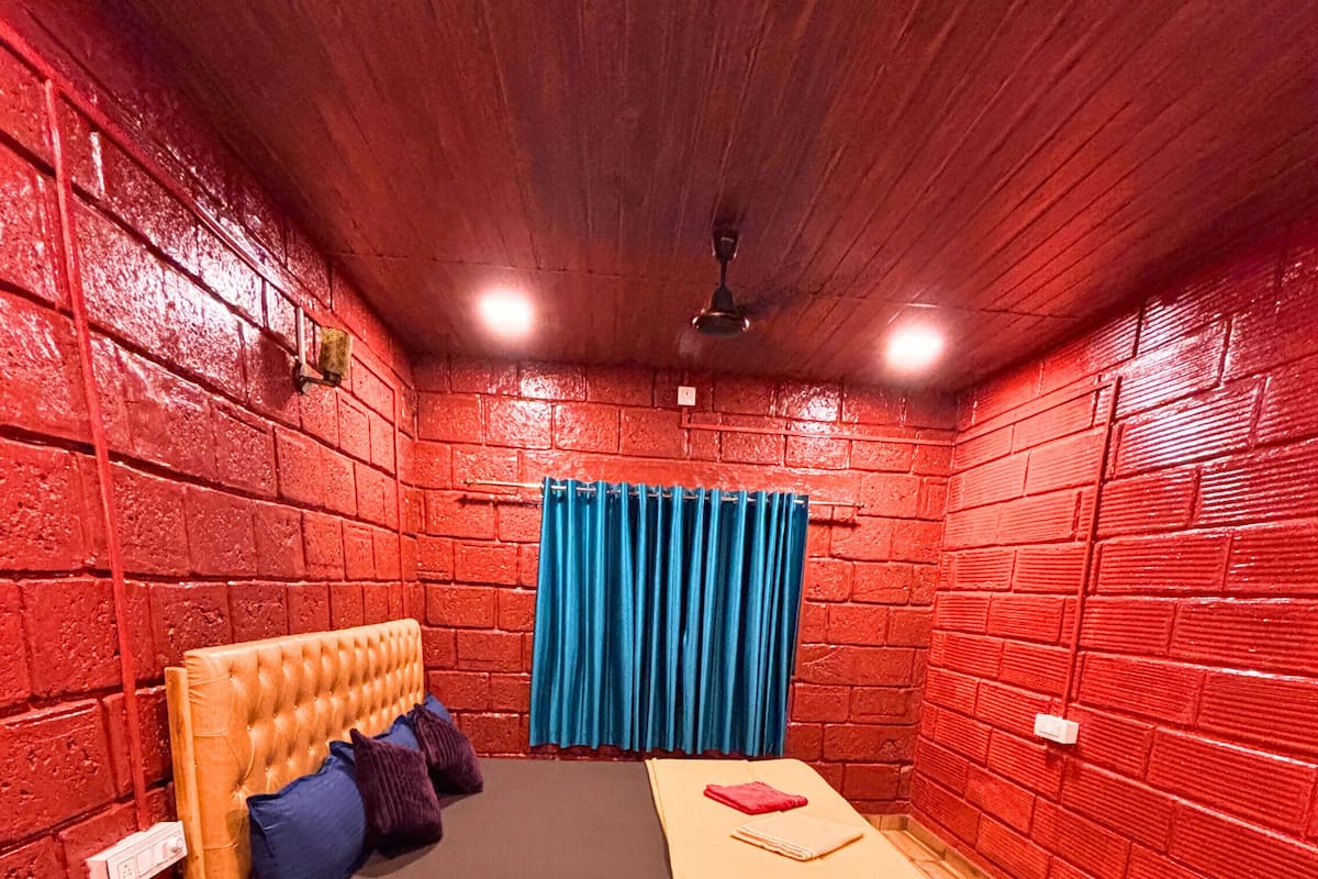 Una habitación con una cama de madera, una cortina azul y suelo de madera.