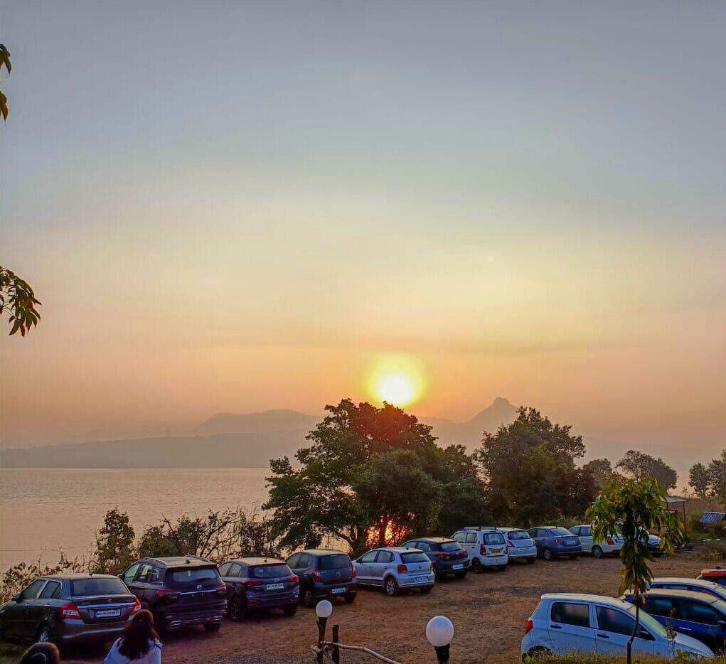 A parking lot with cars and a sunset view.