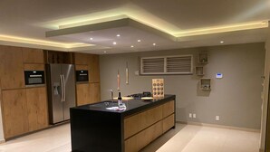A modern kitchen with a central island, built-in appliances, and recessed ceiling lighting. - Romantic Waterfront Villa for 6 (Willemstad)