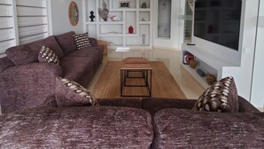 A living room with a sofa, a coffee table, and a TV. - Romantic Waterfront Villa for 6 (Willemstad)