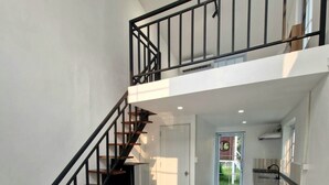 A spacious living area with a staircase, a dining area, and a kitchen. - River view villas (Vang Vieng)