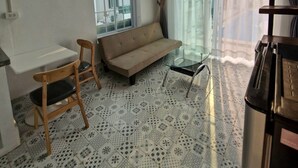 A high-ceiling room with a sofa, a small table, and chairs. - River view villas (Vang Vieng)