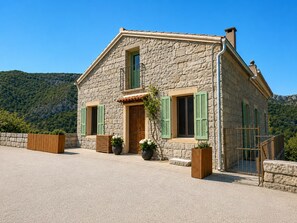 A stone house with a wooden door, green shutters, and potted plants. - CASA ZITELLINI Charming village house in Zoza near the natural swimming pools (Zoza)
