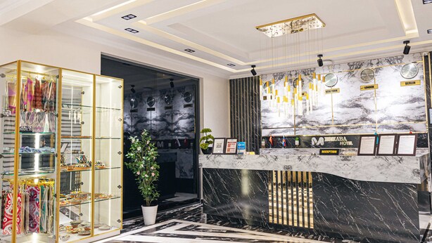 Una recepción de hotel con mostrador de mármol, vitrinas de cristal y un diseño moderno de techo.