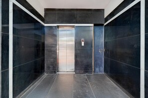 A modern elevator with a control panel, surrounded by dark marble walls and a polished floor. - Classic With Balcony LR Residency (Anekal)