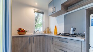 A modern kitchen with wooden cabinets, a gas stove, and a window. - Vigna Sul Mar Family Collection (Comacchio)