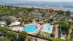 An aerial view of a coastal resort with multiple swimming pools, beach access, and a marina. - Vigna Sul Mar Family Collection (Comacchio)