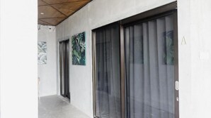 A hallway with a sliding glass door, a wall-mounted artwork, and a door with a keypad lock. - Escotel Krisnantara Canggu (Tibubeneng)