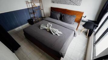 Habitación de hotel con cama, cabecera de madera, una obra de arte abstracta en la pared, una silla negra y una ventana con cortinas.