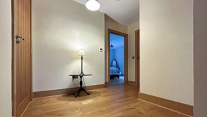 Ein Flur mit Holzboden, einer Tischlampe und einem Bett im Hintergrund.