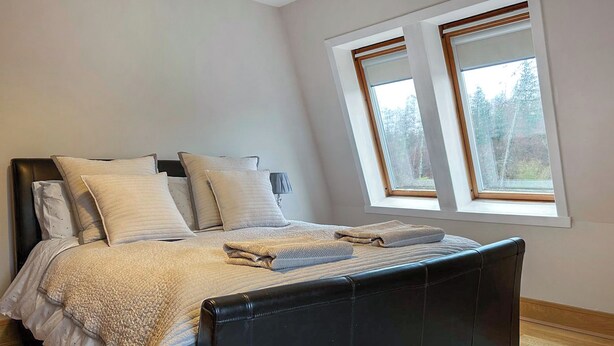 Ein Schlafzimmer mit Bett, Kissen, Nachttisch und Fenster.