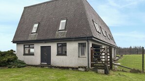 Ein zweistöckiges Haus mit geneigtem Dach, einer Haustür und einer kleinen Veranda.