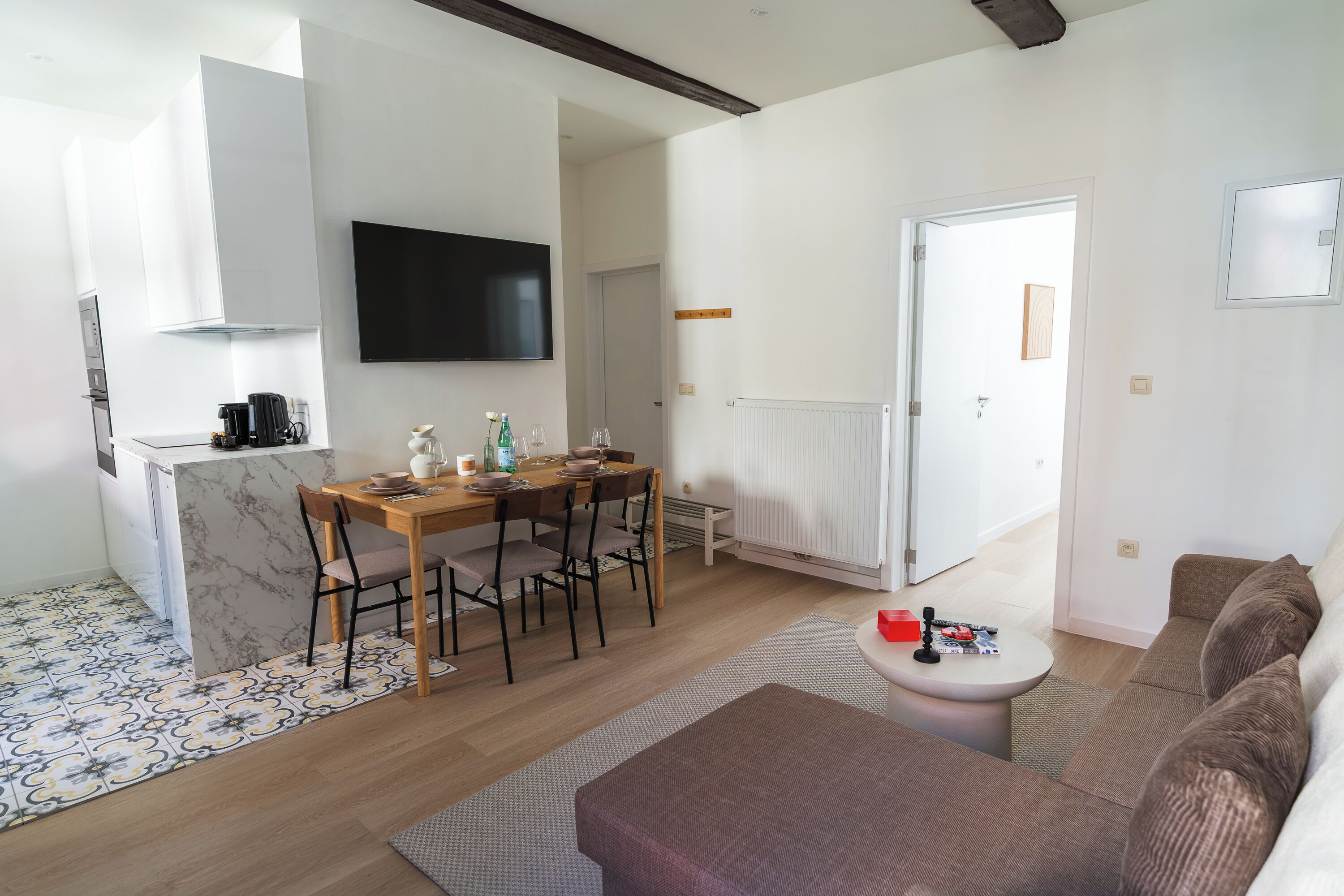 Una cocina moderna con comedor, televisor de pantalla plana y sala de estar con sofá y mesa de centro.