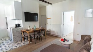 A modern kitchen with a dining area, a flat-screen TV, and a living room with a sofa and a coffee table. - Central Ghent Stylish 1BR&1LR Apt WIFI (Ghent)