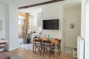 Een eetruimte met een houten tafel, stoelen en een flatscreen televisie aan de muur.