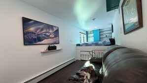 A living room with a large painting, a couch, and a dog. - Cozy Container: A Shipping Container Retreat for Pups & People. (Soldotna)