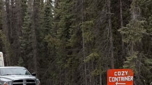 A truck on a snow-covered road with a sign reading 'COZY CONTAINER'. - Cozy Container: A Shipping Container Retreat for Pups & People. (Soldotna)