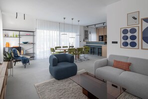 Una sala moderna con sofá, sillón y comedor con sillas.