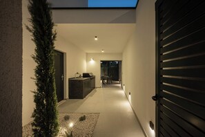 Una cocina moderna con una isla integrada, un comedor con mesa y sillas, y un pasillo que lleva a una puerta.