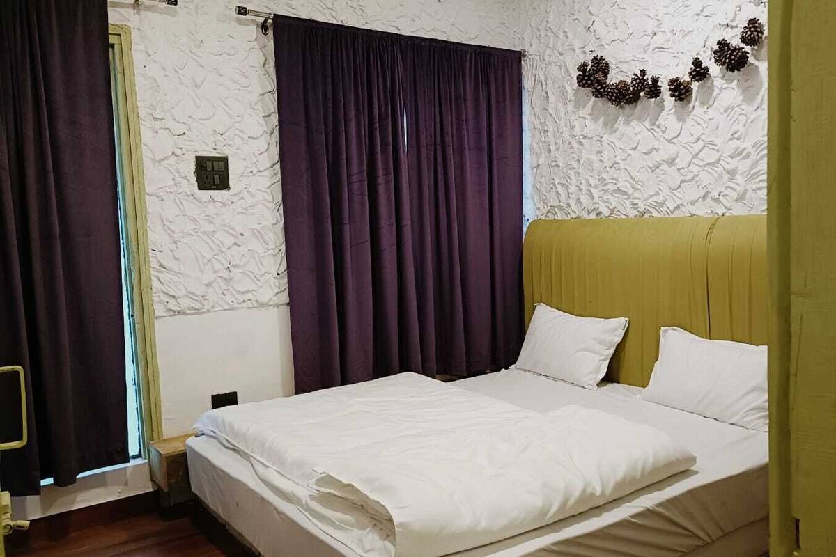 Een kamer met een bed, paarse gordijnen, een witte muur met dennengroen decoraties, en een geel hoofdeinde.