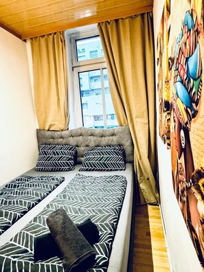 A bed with patterned bedding, a window with curtains, and a wall with a colorful mural. - Spacious Private Room Near FAC Platz (Wien)