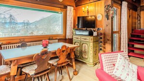 Ein gemütliches Holzinterieur mit einem Esstisch, Stühlen, einem Fernseher und einer roten Treppe.