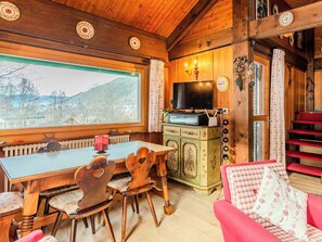 Ein gemütliches Holzinterieur mit einem Esstisch, Stühlen, einem Fernseher und einer roten Treppe.