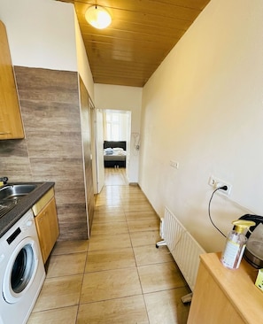 Une cuisine équipée d’un lave-linge, d’un radiateur et dotée d’un plafond en bois.