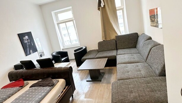Un salon moderne avec un canapé, des fauteuils, une table basse et un lit.