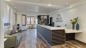 A reception area with a modern design, a reception desk, and a seating area with a sofa. - Boutique Hotel | Rooftop Ocean Views + Pool + Hot Tub | Walk to Everything (Laguna Beach)