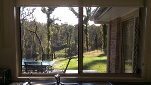 Una cucina con un lavello in acciaio inossidabile e una finestra che si affaccia su una zona verde con alberi.