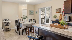 A kitchen with a dining area, a baby high chair, and a kitchen island with a sink. - Mount Pocono Escape • Firepit + Game Room • Near Trails + Lakes | Poconos Fun (Mount Pocono)