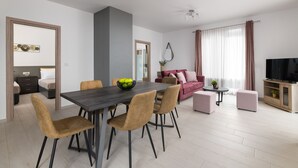 A modern living room with a dining area, a sofa set, a TV, and a small table with a plant. - Elysian Luxury Residence -Melia (Stegna)