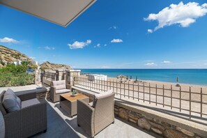 A terrace with wicker furniture, a view of the sea, and a stone wall.