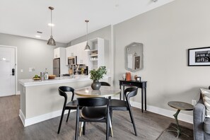 A modern kitchen with white cabinets, a central island, and pendant lighting. - Walkable Hillsboro Village | Terrace + Parking | Near Vanderbilt + Music Row (Nashville)