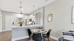 A modern kitchen with a central island, black chairs, and a dining table. - Walkable Hillsboro Village | Terrace + Parking | Near Vanderbilt + Music Row (Nashville)