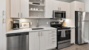 Une cuisine moderne dotée d’appareils électroménagers en acier inoxydable, de meubles de couleur bois clair et d’un plan de travail blanc.