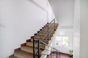 A staircase with a metal railing, a window with a view of the outside, and a potted plant on the landing.