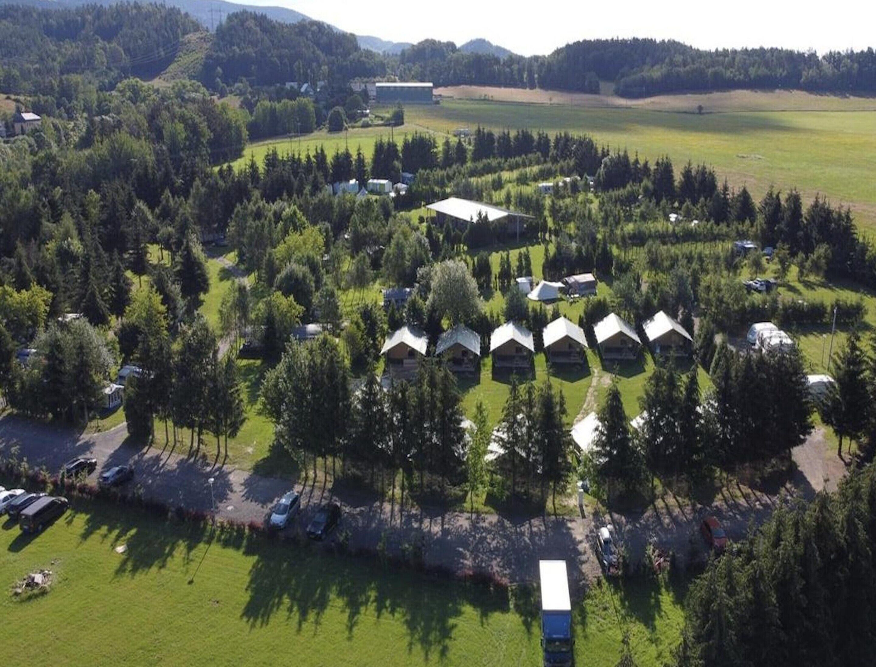 An aerial view of a campground with several cabins, a large building, and a parking area.