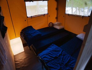 A compact room with two beds, a window, and a lamp.